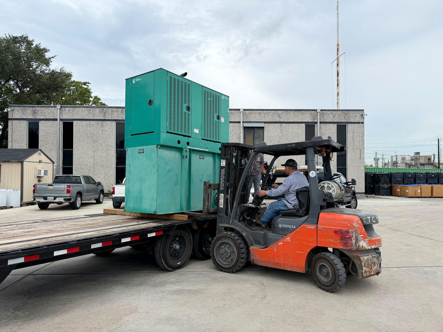 Cummins standby generator being loaded onto a flatbed trailer by forklift